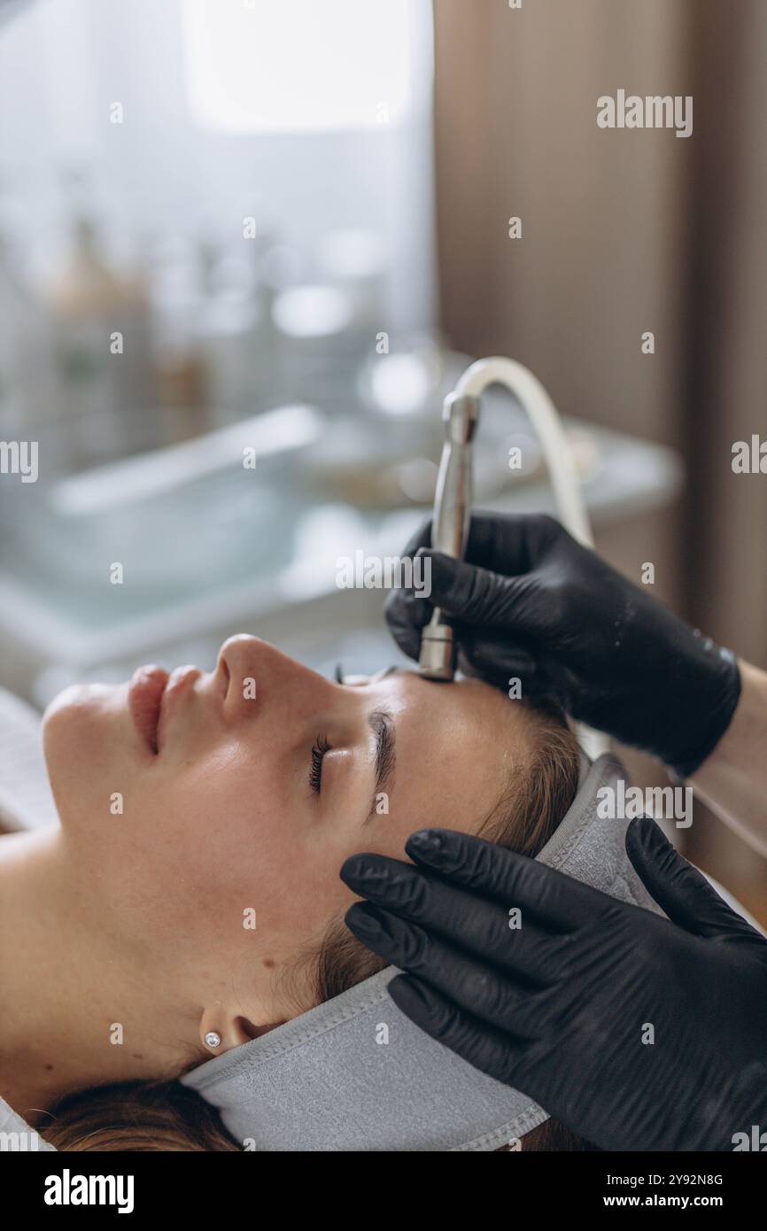 Professionelle Dermatologin in medizinischen Handschuhen führt Mikrodermabrasion auf Frau in einem Schönheitssalon Stockfoto