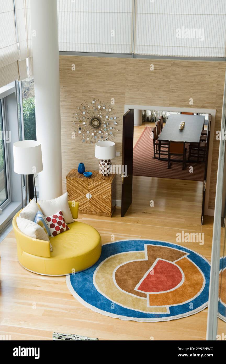 Blick auf den runden Teppich und die Sitzgelegenheiten vom Zwischengeschoss in einem modernen Designer-Haus, London, Großbritannien Stockfoto