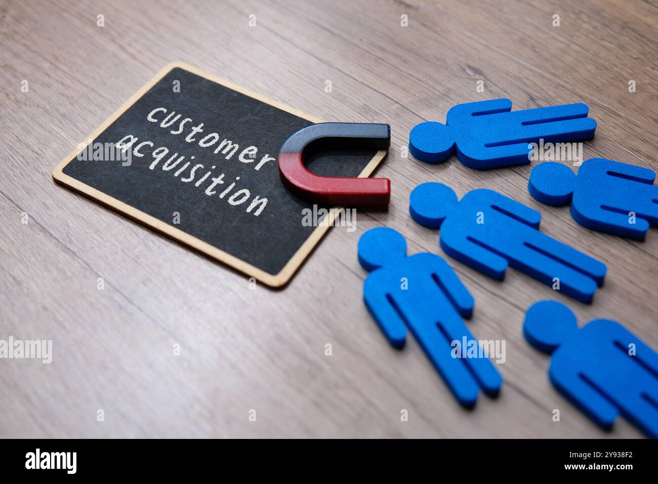 Ein Schwarzes Brett mit den Worten „KUNDENAKQUISE“ und „Magnet“ locken Kunden an. Geschäfts- und Marketingkonzept. Stockfoto