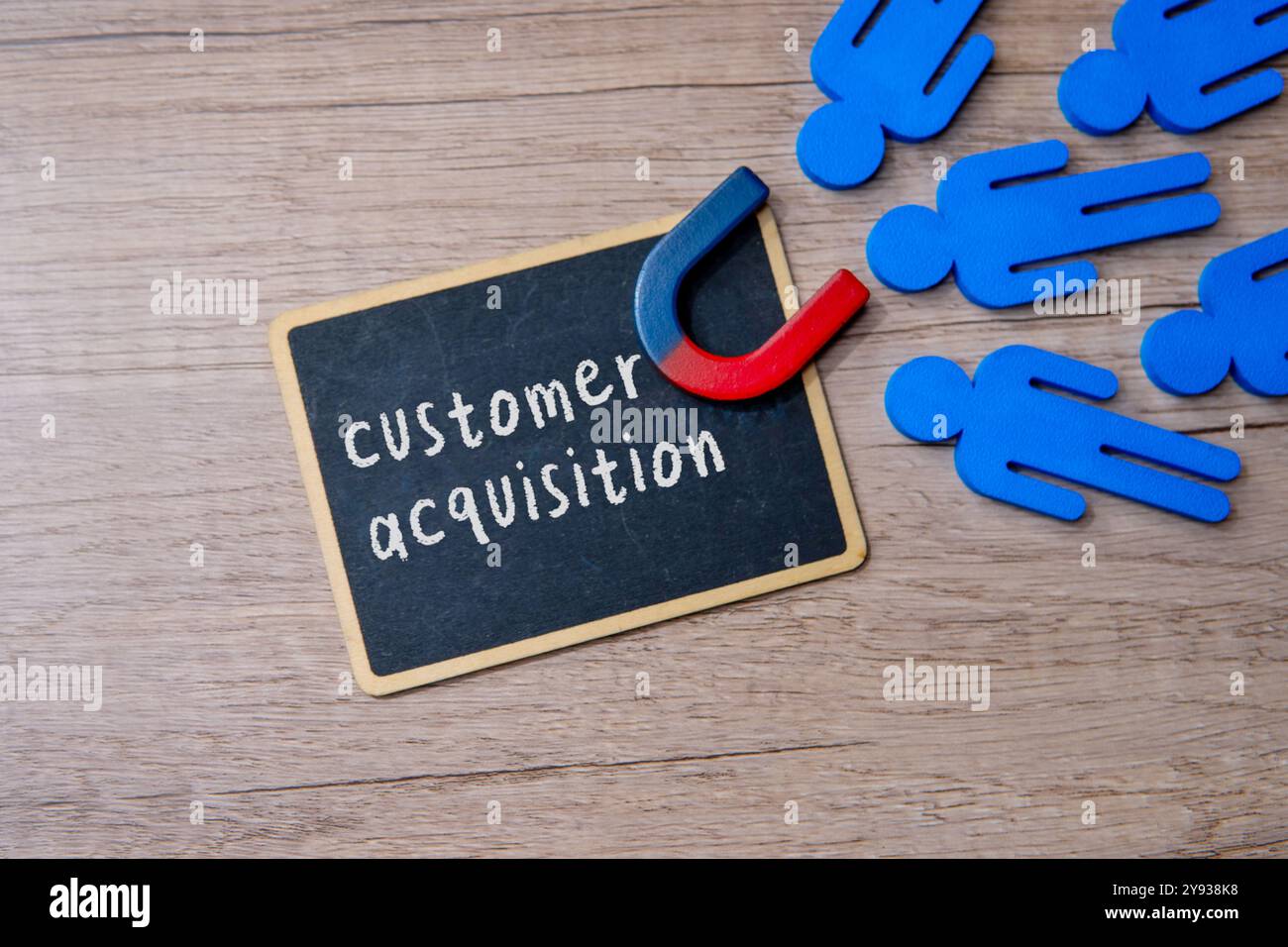 Ein Schwarzes Brett mit den Worten „KUNDENAKQUISE“ und „Magnet“ locken Kunden an. Geschäfts- und Marketingkonzept. Stockfoto
