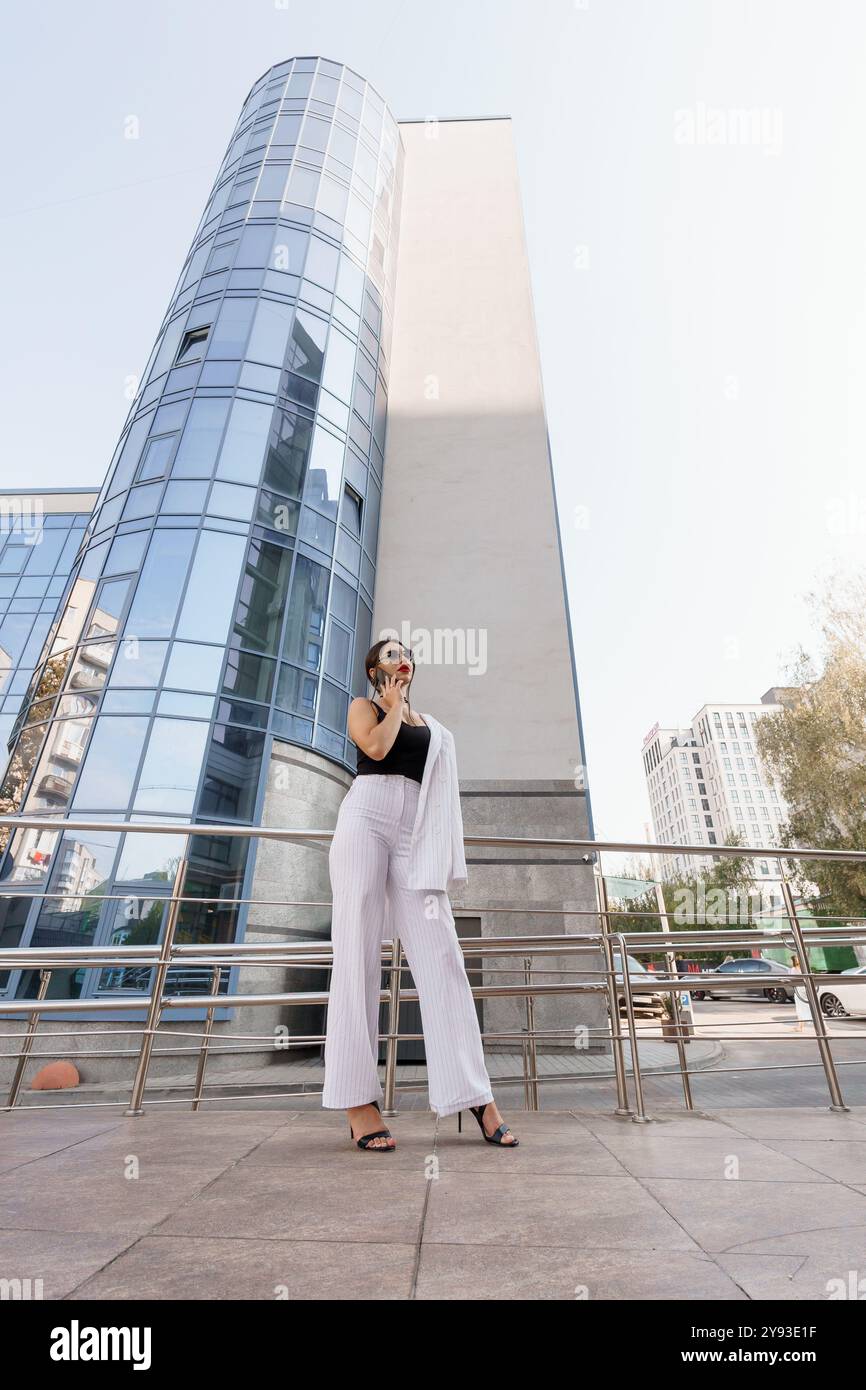 Eine selbstbewusste Geschäftsfrau, die elegant vor einem modernen Glasgebäude steht. Stockfoto