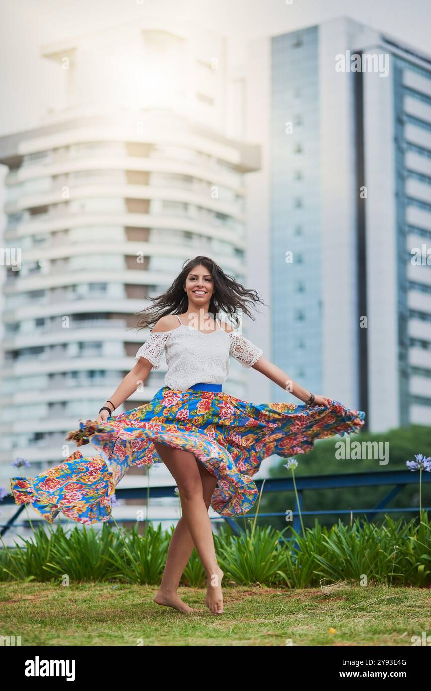 Glücklich, Frau tanzen und Porträt mit wilder Freiheit und urbanem Park mit Lächeln im Freien mit Reisen und Urlaub. Stadt, Urlaub und Wochenende mit Rock Stockfoto