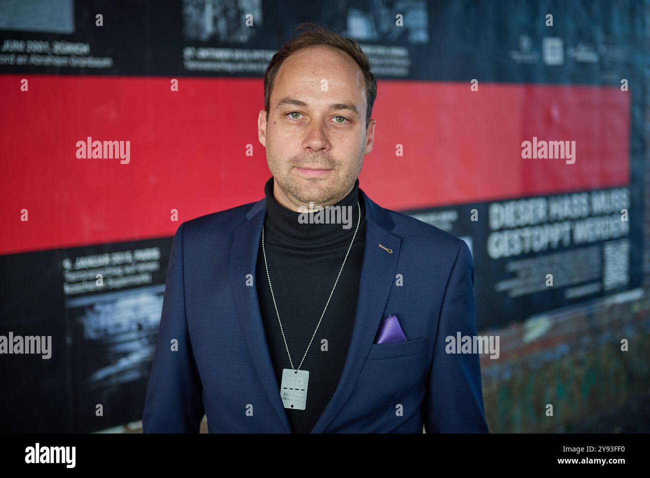 Kampagnenstart der Aktionswochen gegen Antisemitismus am 08.10.2024 mit einem 10 Meter langen Plakat am Hackeschen Markt in Berlin. Foto: Projektleiter der Aktionswochen gegen Antisemitismus Nikolas Lelle vor dem Plakat die Amadeu Antonio Stiftung und das Anne Frank Zentrum machen im Rahmen der diesjaehrigen Aktionswochen gegen Antisemitismus auf die anhaltende Bedrohung von Juedinnen und Juden aufmerksam. Mit der bundesweiten Plakatkampagne Terror gegen Juden erinnern die beiden Organisationen seit Dienstag bundesweit an die Opfer judenfeindlicher Straftaten seit 1945. Ziel der Kampagne ist d Stockfoto