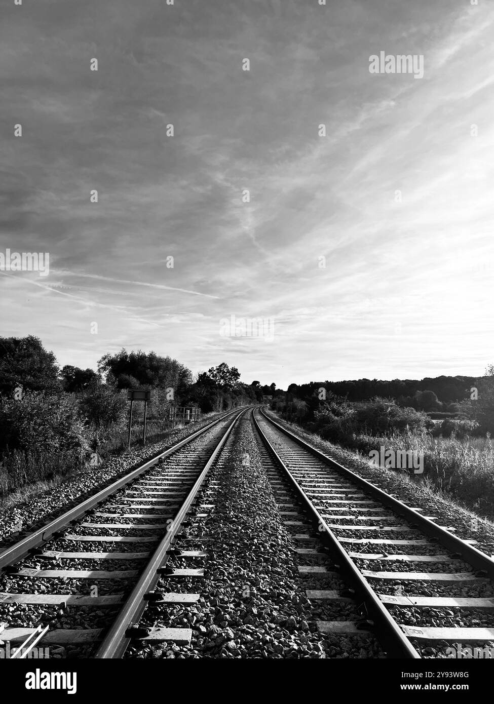 Ein Schwarzweißfoto im Porträt von zwei leeren Bahngleisen, aufgenommen in Suffolk, England. Stockfoto