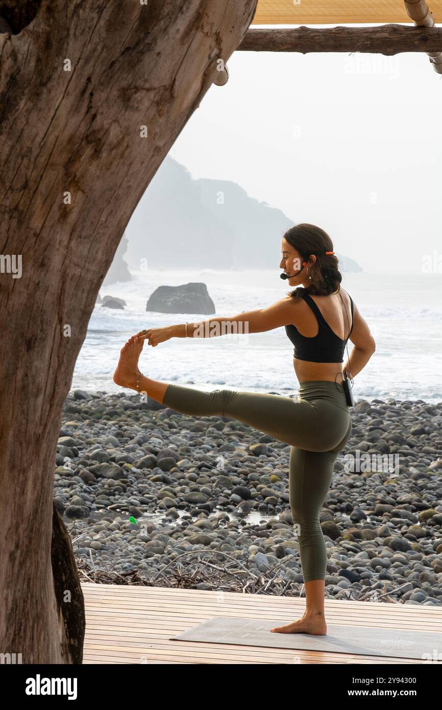 Seitliche Ansicht der Frau spielt die Utthita Hasta Padangusthasana Yoga-Pose auf einer Strandterrasse in Mizata, La Libertad, El Salvador. Sie gleicht Gracefu aus Stockfoto