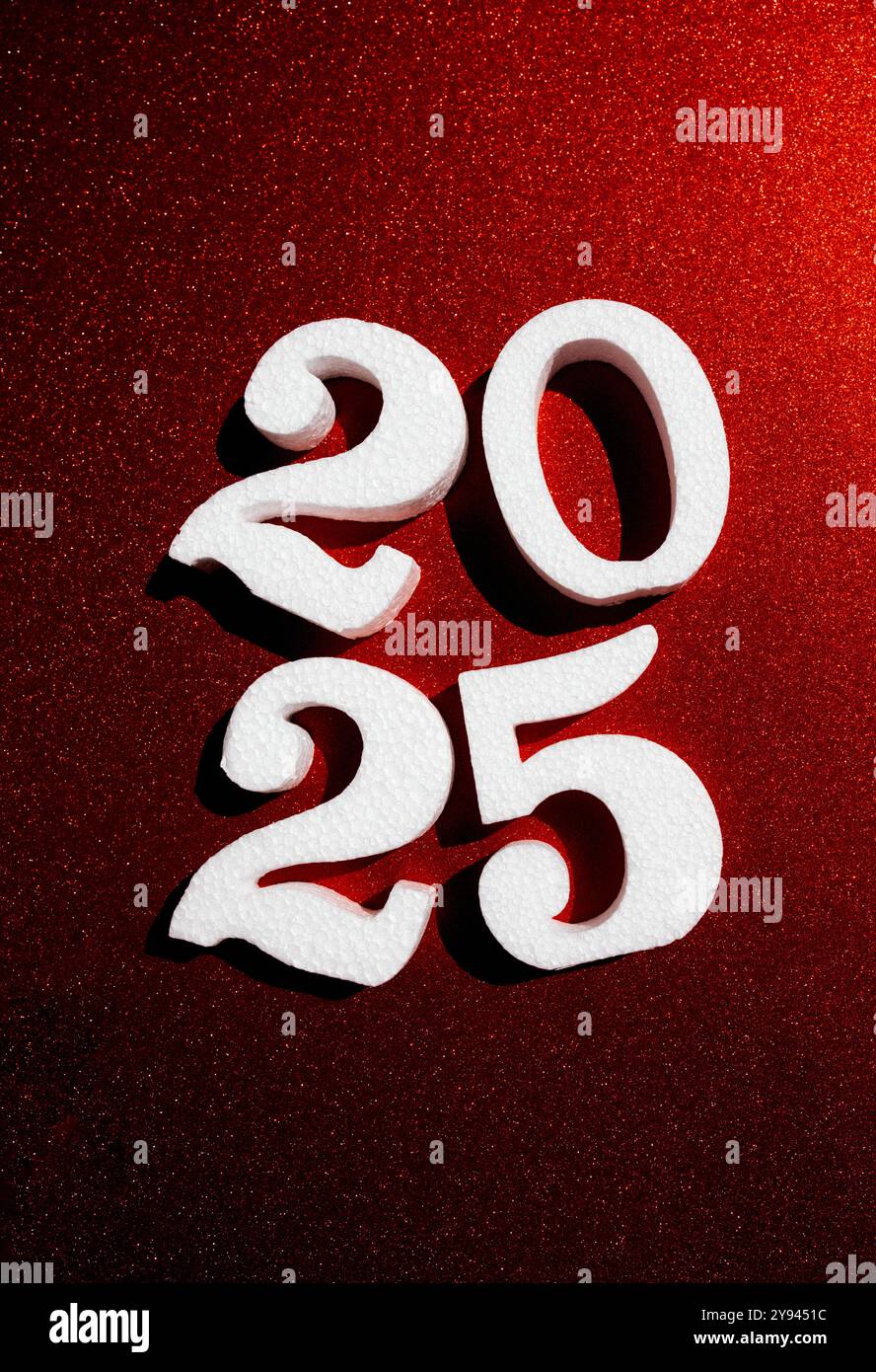 Weiße 3D-Zahlen 2025 vor einem leuchtend roten Glitzerhintergrund, die die feierliche Essenz des neuen Jahres festhalten. Stockfoto