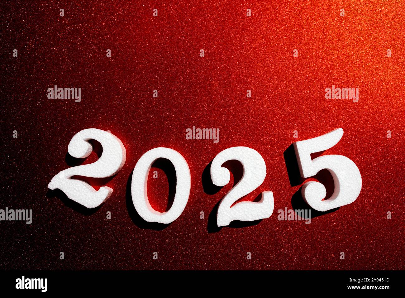 Ein markantes Bild mit strukturierten weißen Ziffern von 2025 auf einem leuchtend roten Glitzerhintergrund, das die Begeisterung für die bevorstehende neue Yah symbolisiert Stockfoto