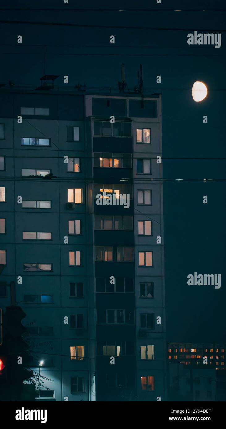 Das Nachtfoto des mehrstöckigen Plattenbaus aus der Sowjetzeit mit Licht an den Wohngebäuden und hellem Mond am Himmel in Nowosibirsk, Russland. Stockfoto