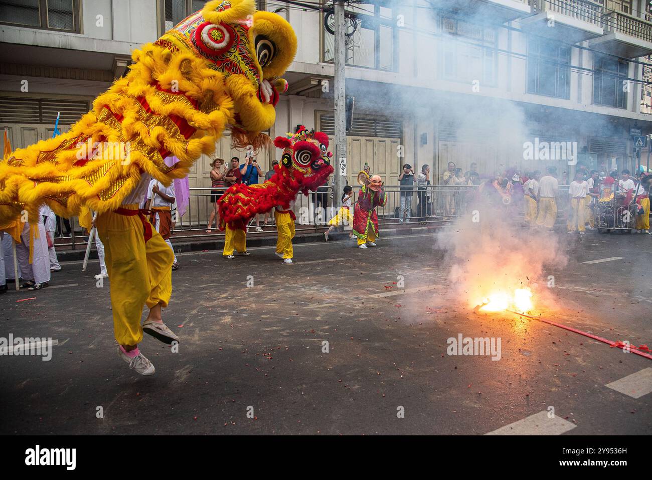Bangkok, Thailand. Oktober 2024. Tänzer führen einen Löwentanz in der Nähe der Feuerwerkskörper während des vegetarischen Festivals im Yaowarat im Chinatown in Bangkok auf. Das annaul vegetarische Festival in Thailand findet vom 3. Bis 12. Oktober 2024 statt und die Anbeter verzichten auf tierische Produkte während der neun Tage, und dies fällt mit der Feier der neun chinesischen Kaiser-Götter zusammen. Quelle: SOPA Images Limited/Alamy Live News Stockfoto
