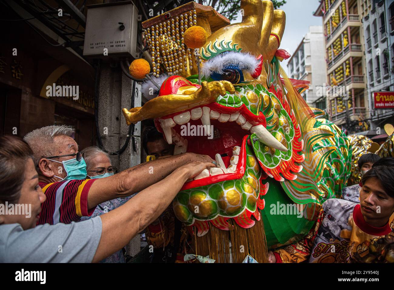 Bangkok, Thailand. Oktober 2024. Die Menschen geben dem Lion Geld, während Tänzer während des vegetarischen Festivals im Yaowarat the Chinatown in Bangkok einen Löwentanz aufführen. Das annaul vegetarische Festival in Thailand findet vom 3. Bis 12. Oktober 2024 statt und die Anbeter verzichten auf tierische Produkte während der neun Tage, und dies fällt mit der Feier der neun chinesischen Kaiser-Götter zusammen. (Foto: Peerapon Boonyakiat/SOPA Images/SIPA USA) Credit: SIPA USA/Alamy Live News Stockfoto