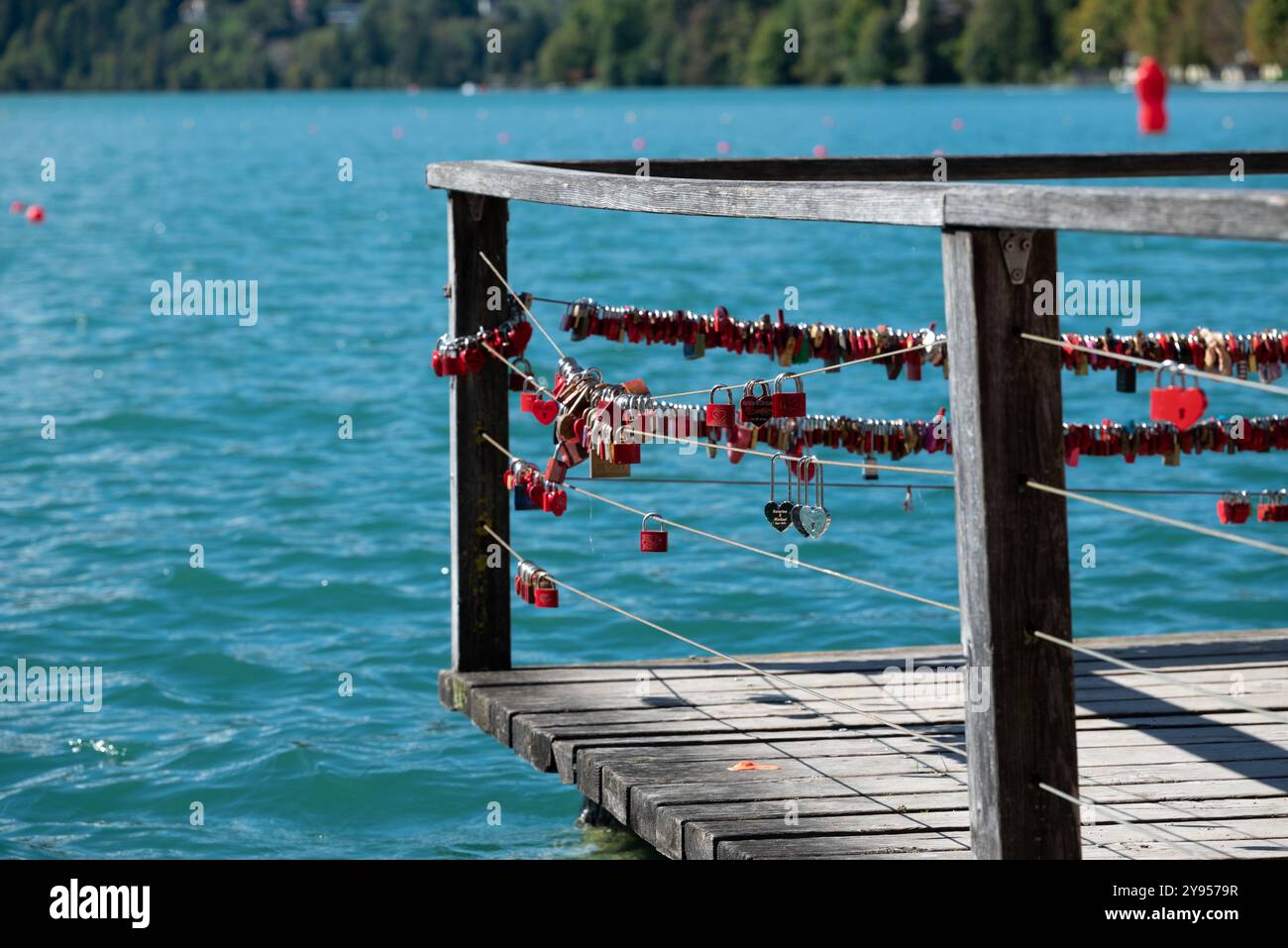 Love Locks auf einem Pier - Eine Nahaufnahme einer Sammlung von Love Locks, die an einem hölzernen Geländer befestigt sind, ein Symbol für Engagement und Versprechen. Rote Boje i Stockfoto