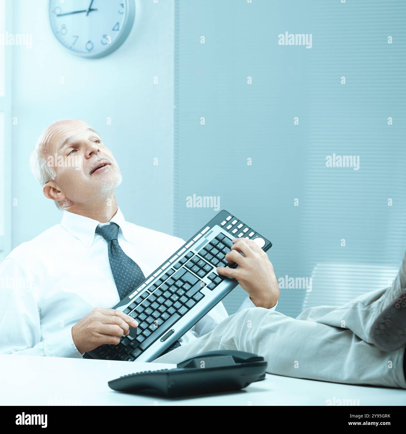 Das Büro fängt einen Geschäftsmann in aller Stimmung ein, der humorvoll sein Keyboard spielt wie ein Musikinstrument Stockfoto