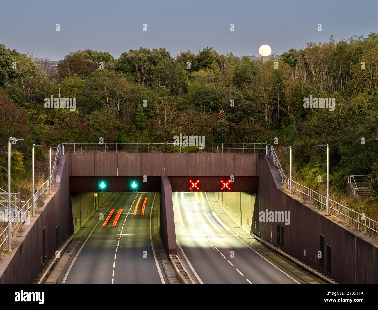 Der Verkehr fließt auf dem A55 North Wales Expressway am Conwy Tunnel, während der Mond darüber steigt. Stockfoto