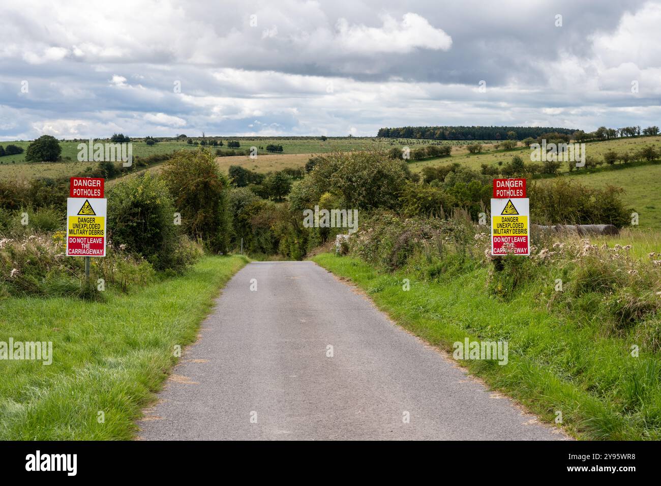 Schilder warnen vor nicht explodierten militärischen Trümmern auf einer Straße durch die Imber Range, einem Trainingsgebiet der britischen Armee in der Salisbury Plain in England. Stockfoto