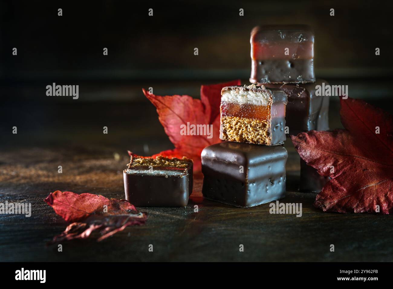 Dominostein, überzogene Konfektion aus Lebkuchen, Gelee und Marzipanüberzug mit Schokolade, deutsche Festtagsbonbons, gestapelt mit rotem herbstlea Stockfoto