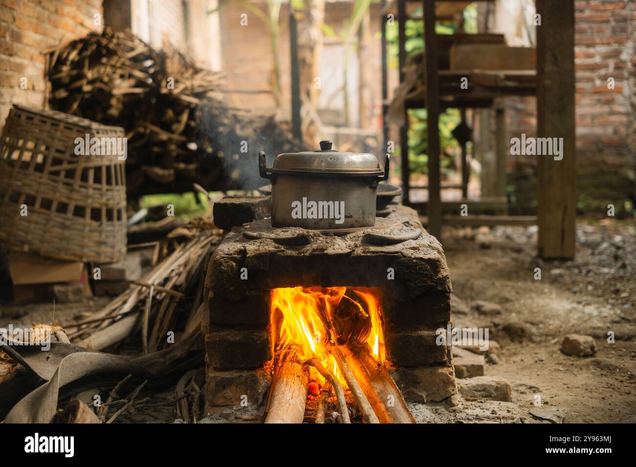Rustikaler Holzofen im Freien mit Flammen und Metalltopf in traditioneller Küche Stockfoto