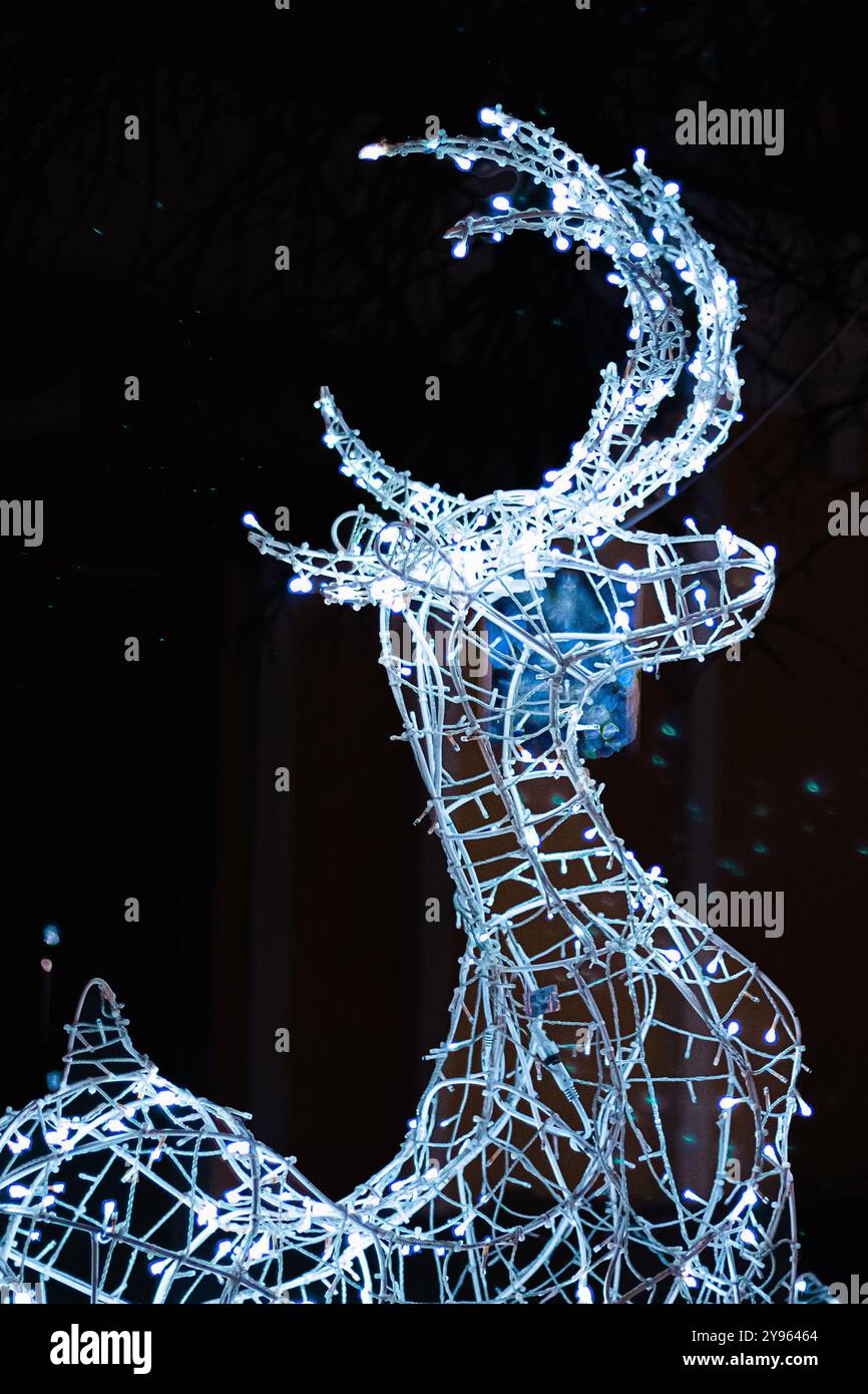 Weihnachtshirsch mit Lichtern auf schwarzem Hintergrund. Neujahrsdekoration der Stadt. Stockfoto