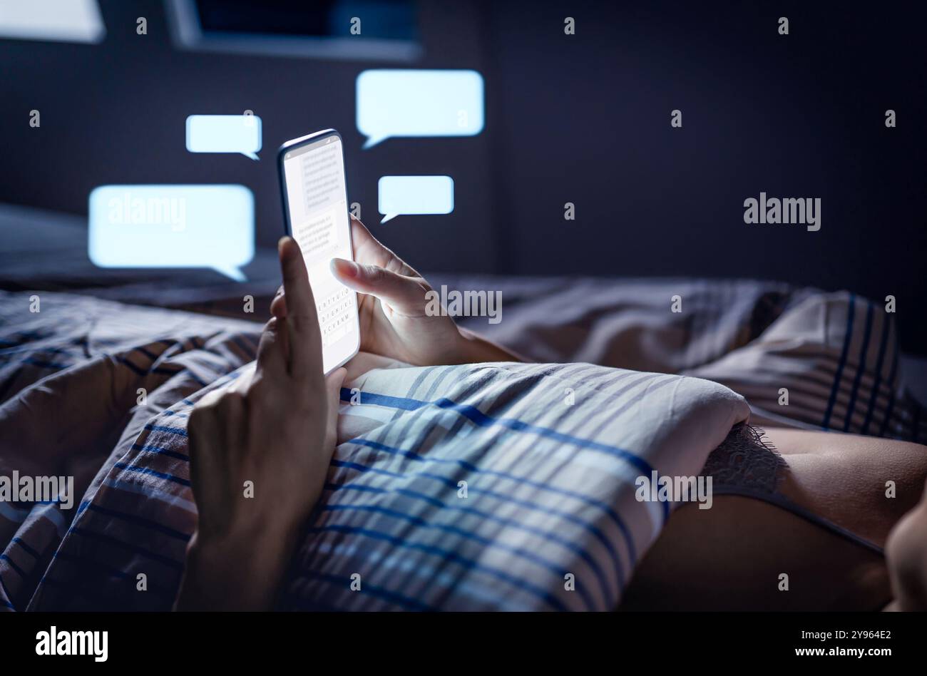 SMS im Bett vor dem Schlafengehen. Frau mit Smartphone. DM, Direktnachricht. SMS-Betrug. Bildschirmzeit. Chatten Sie mit dem Mobiltelefon. Geheim oder Klatsch. Stockfoto