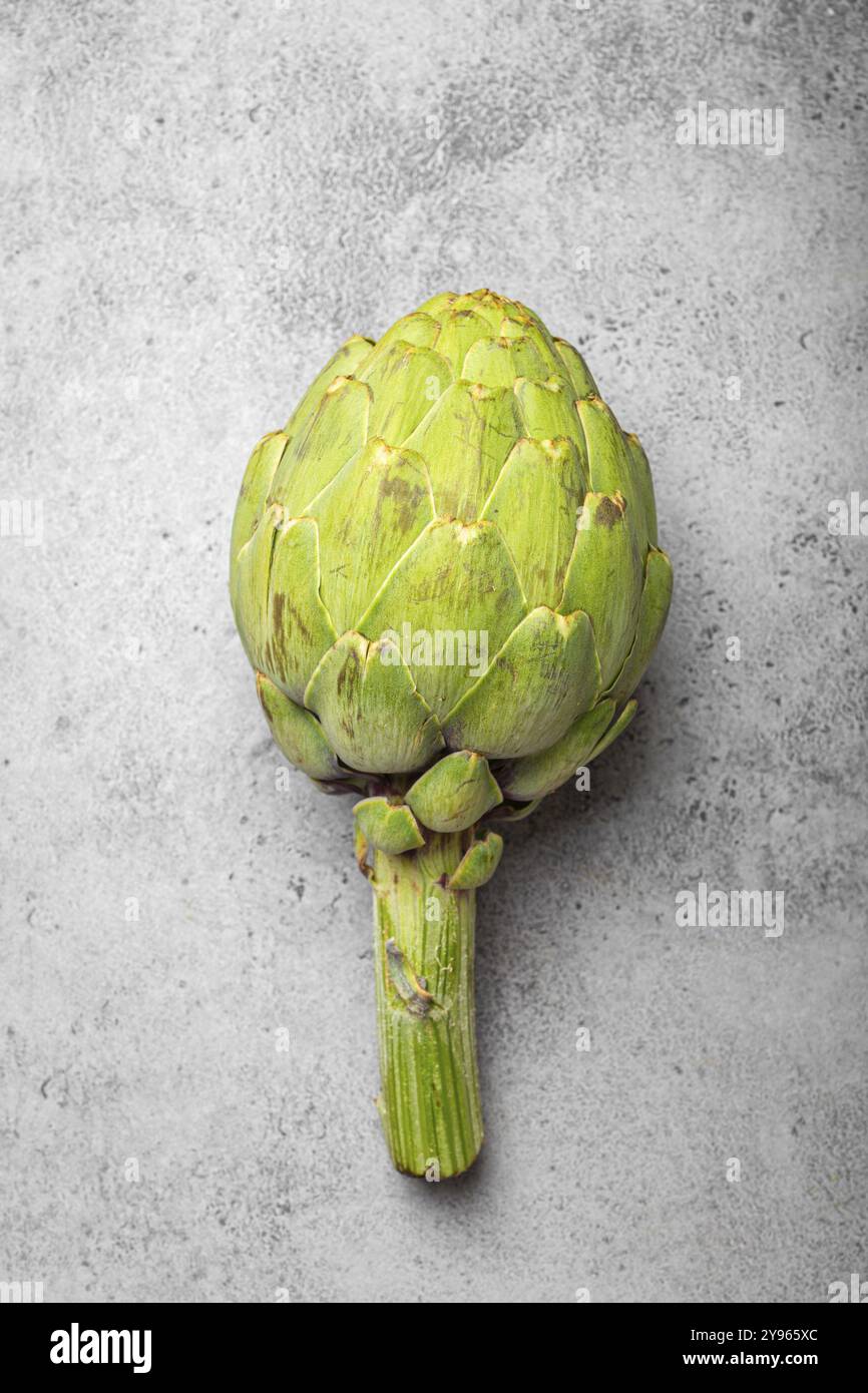 Frische rohe Bio-Farm eine Artischocke auf grauem rustikalem Stein Hintergrund von oben Ansicht, gesunde Artischocken in ausgewogener Ernährung und Kochkonzept, Food Phot Stockfoto