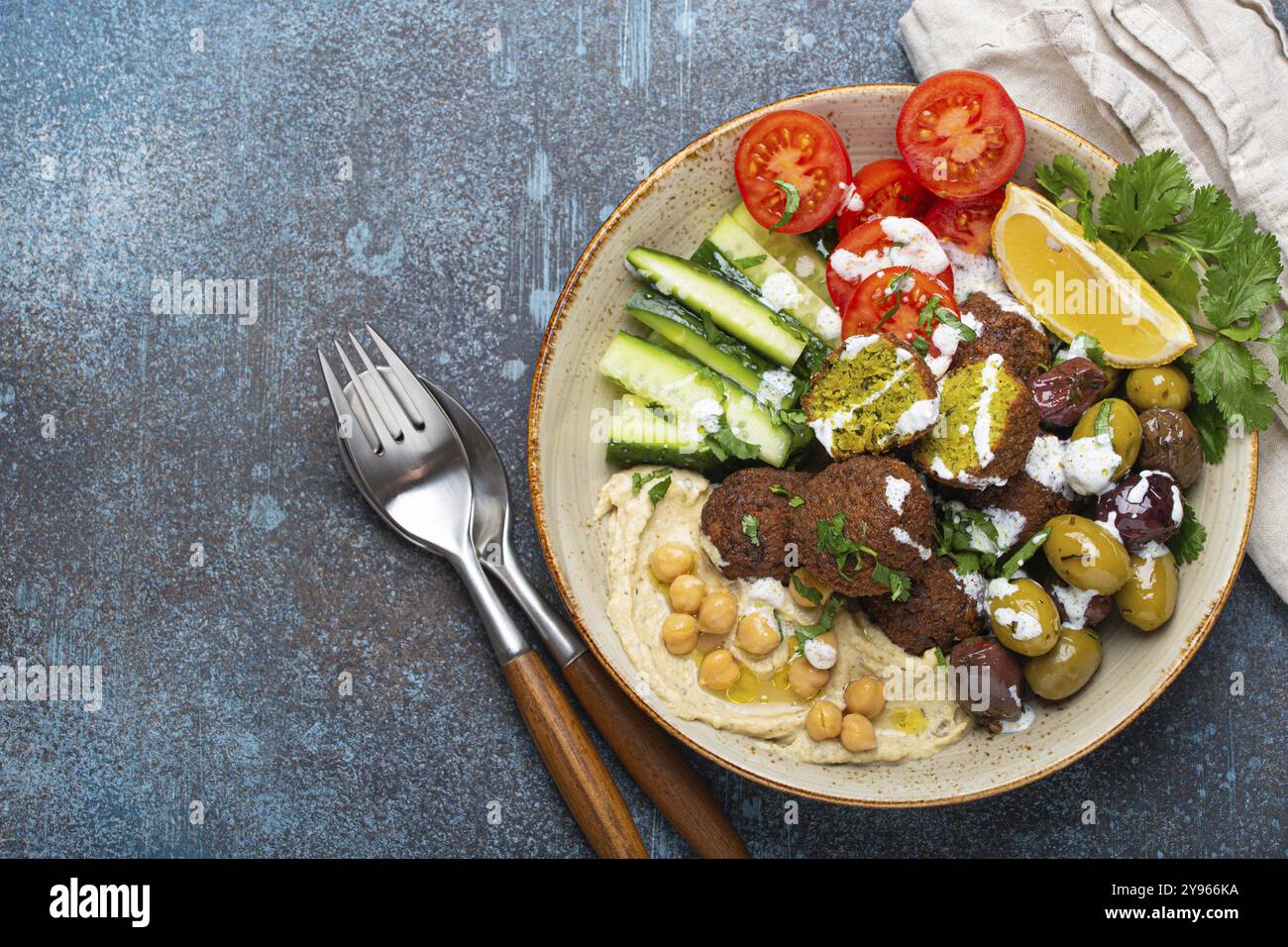 Falafel Salatschale mit Hummus, Gemüse, Oliven, Kräutern und Joghurtsauce. Vegane Mittagsplatte, Blick von oben auf rustikalen Steinhintergrund, gesunde Mahlzeit mit f Stockfoto