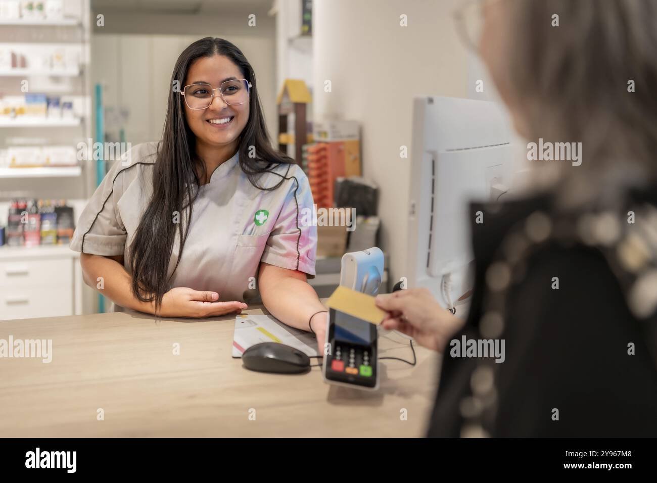 Rückansicht einer nicht erkennbaren Reifen Frau, die mit kontaktloser Technik in einer Apotheke bezahlt Stockfoto