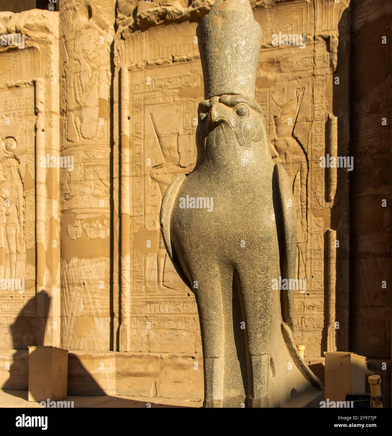 Bewundern Sie die majestätische Statue von Horus, dem Himmelsgott, der mit der Krone von Ägypten geschmückt ist, während er seine Herrschaft vom Tempel von Edfu im Land aus überwacht. Stockfoto