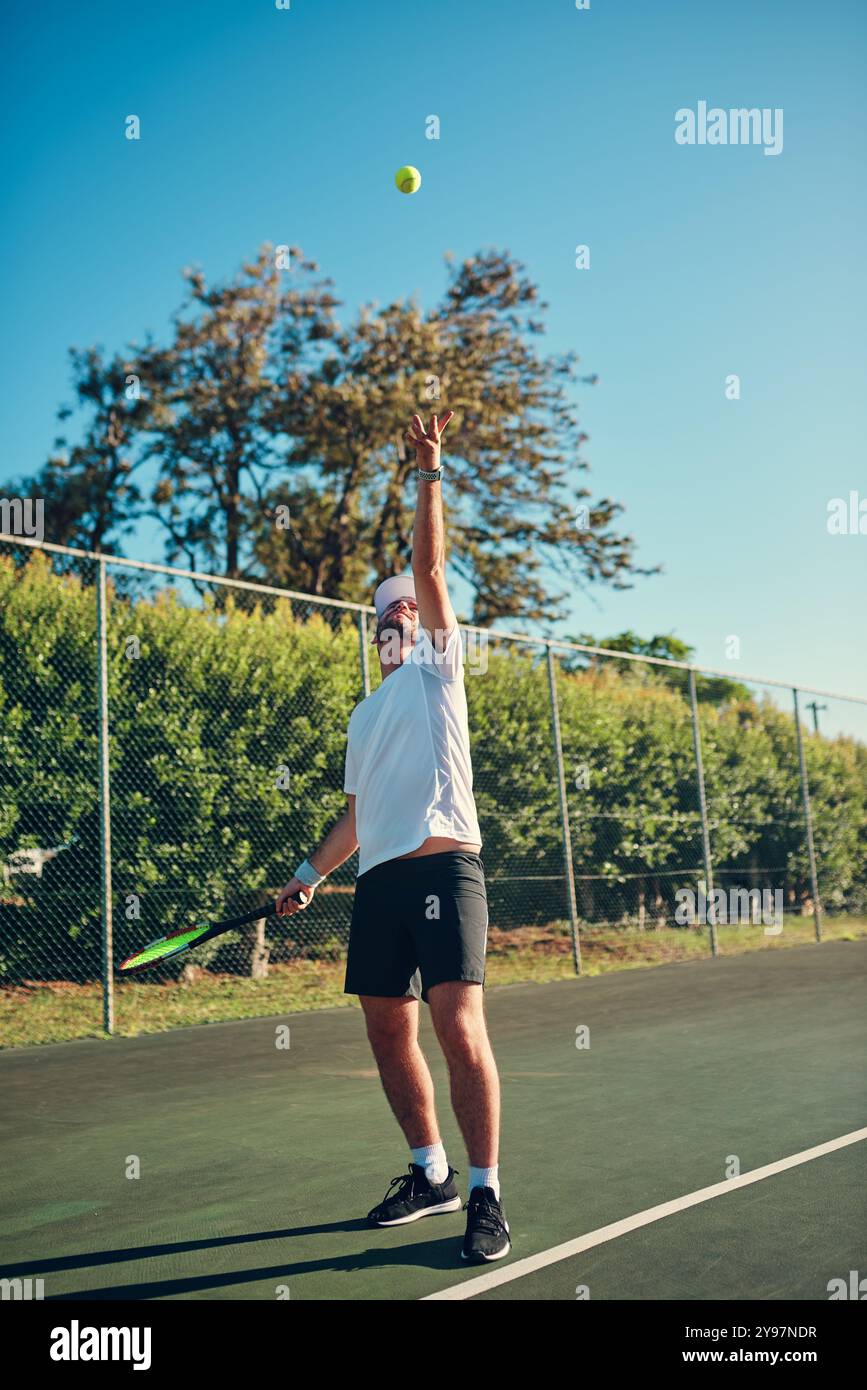 Mann, Tennis und Sport mit Ball in der Luft zum Servieren, Spielen oder Matchen auf dem Outdoor Court. Junge, männliche Person oder Athlet mit Schaukel im Training oder Stockfoto