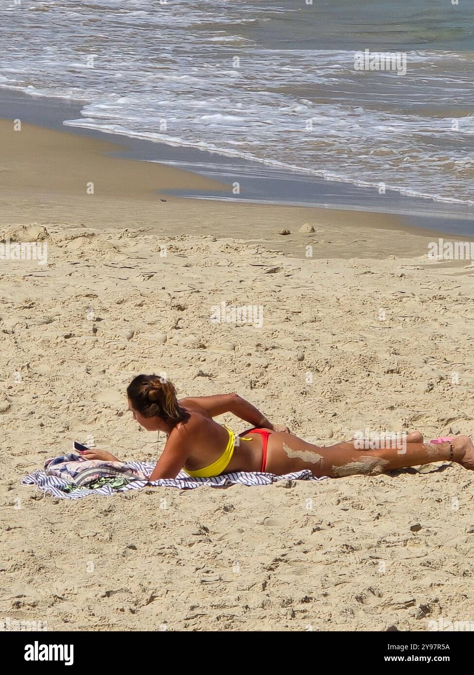 Eine Frau, die sich am Strand in Tel A Israel sonnt. - Smartphone-aufgenommenes Stockfoto