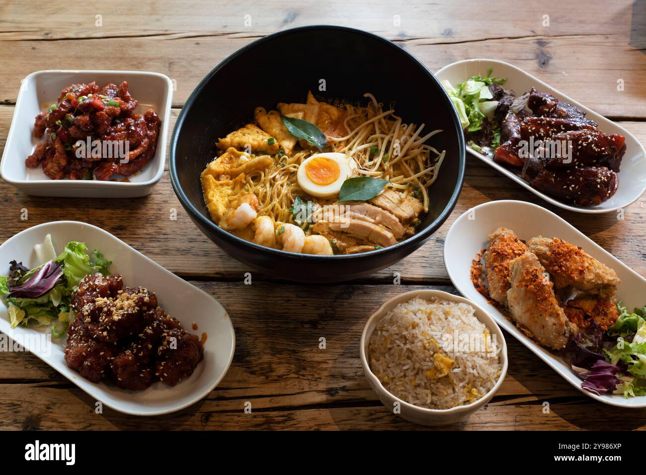 Ausgewählte asiatische Gerichte wie Curry Laksa, süßes und saures Huhn, koreanische gewürzte bbq Wings und Kimchi Stockfoto