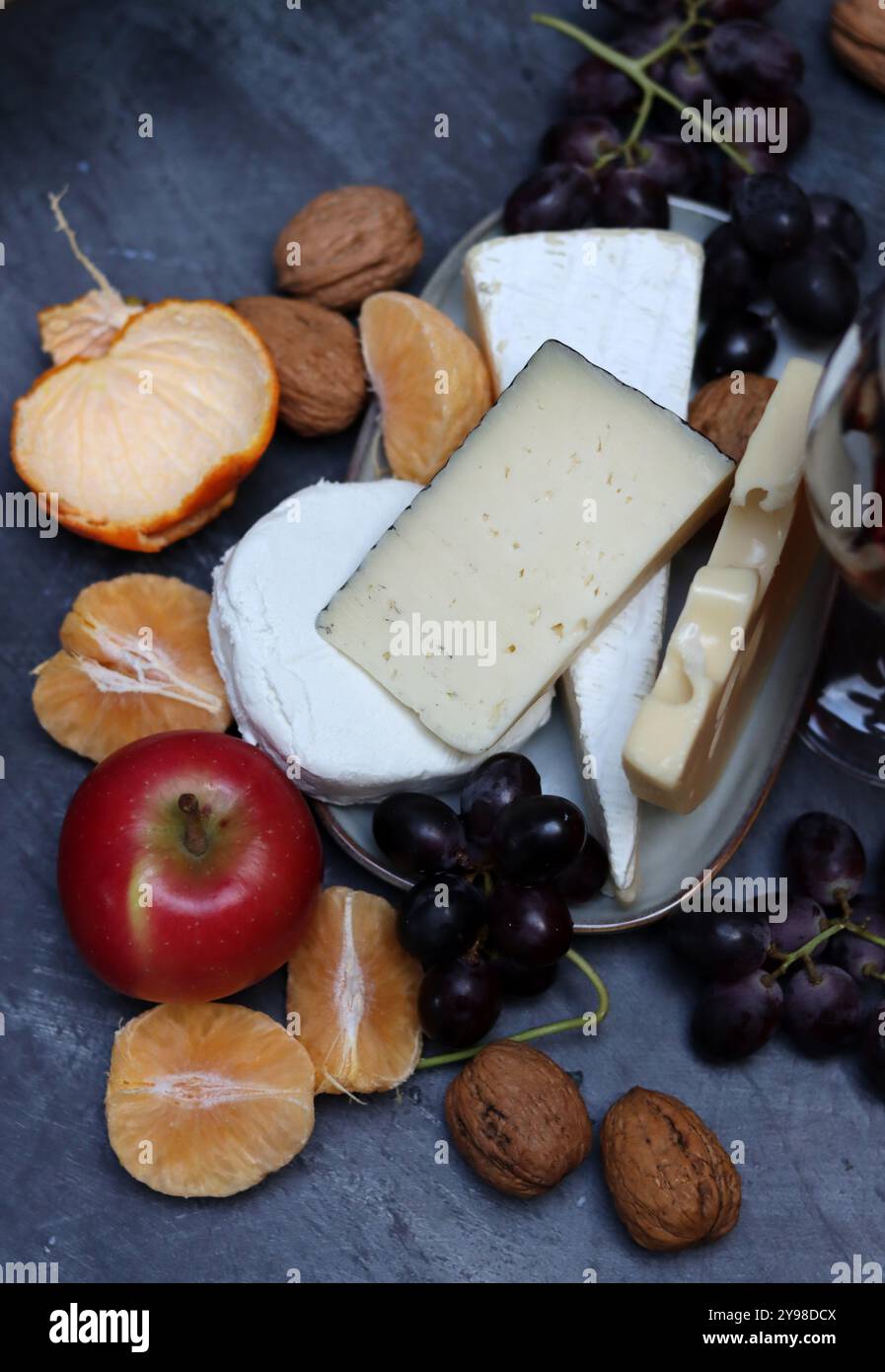 Teller mit Käse, Trauben und Äpfeln auf grauem Hintergrund mit Kopiertempo. Stockfoto