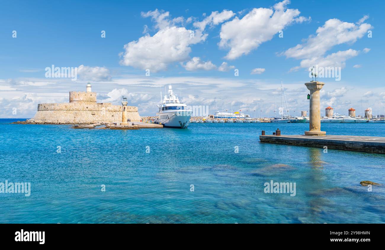 Malerischer Blick auf den Hafen von Mandraki in Rhodos, Griechenland, mit der Festung St. Nikolaus und dem Ort des Kolosses von Rhodos. Stockfoto