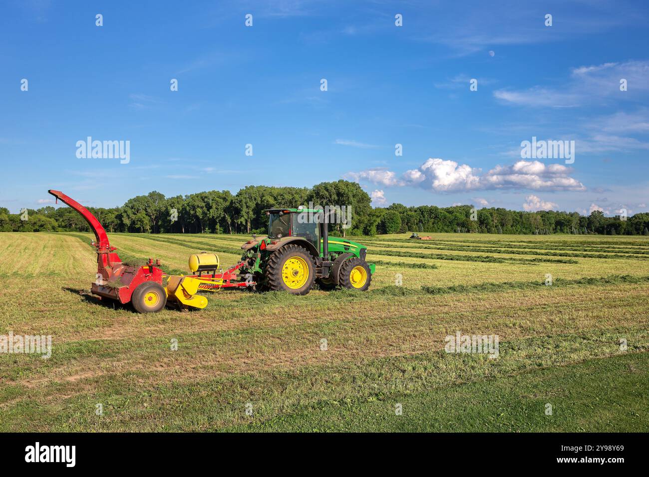 Pulaski, WI – 29. Juli 2020: John Deere-Traktor erntet frisch geschnittene Luzerne auf einem Feld. Das Unternehmen mit Hauptsitz in Moline, Illinois, ist eine Weltgesellschaft Stockfoto