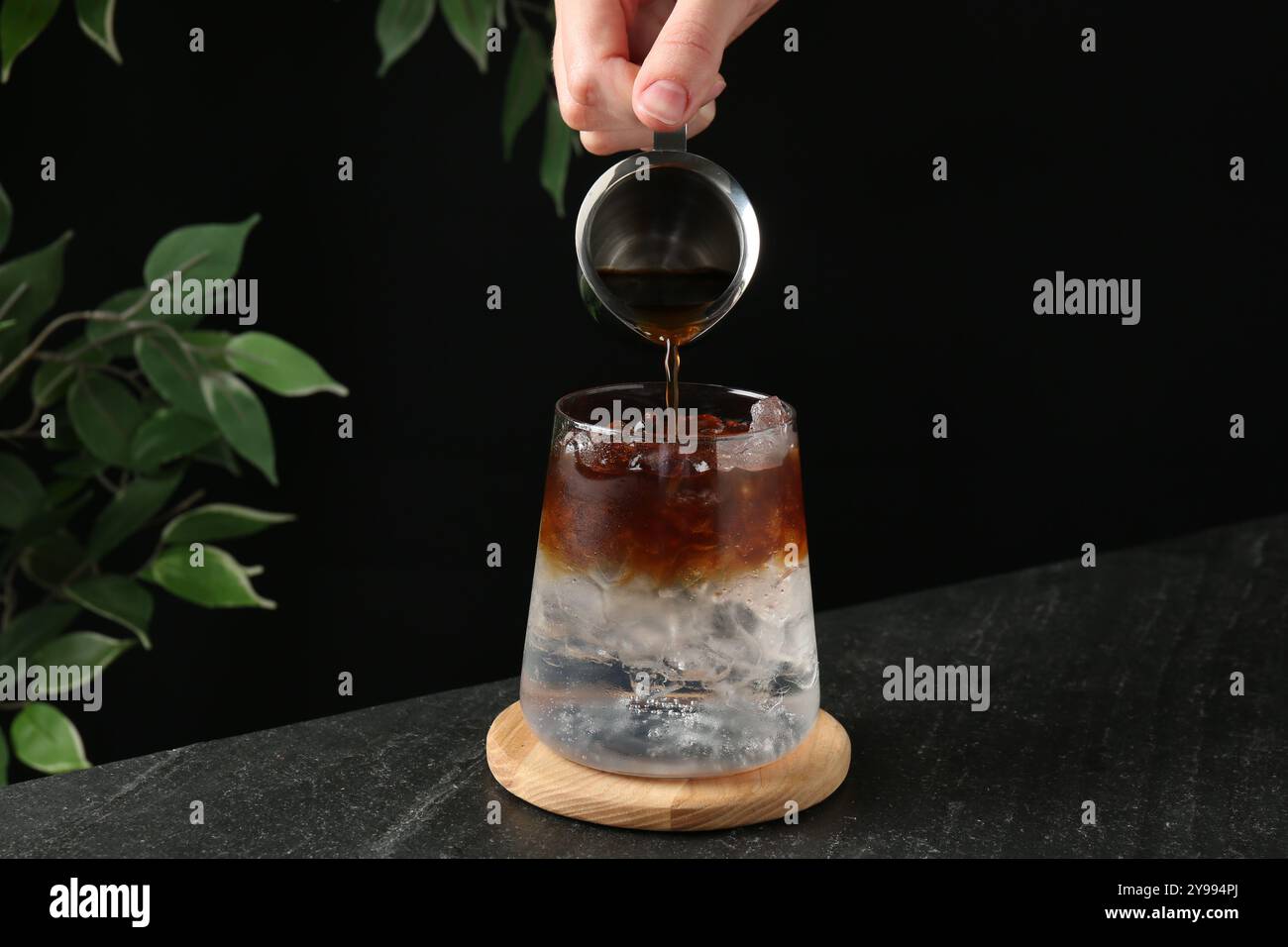 Frau macht erfrischenden Espresso Tonic Drink am dunklen Tisch, Nahaufnahme Stockfoto