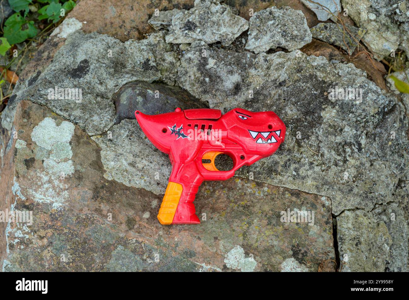 Eine rote Spielzeugpistole in Dinosaurierform Stockfoto