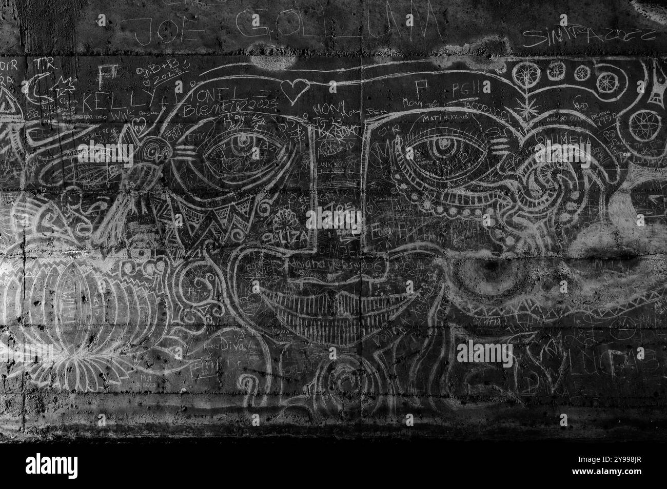 Die Graffiti-Kunst deckt Tunnelwände ab und verschmilzt abstrakte Gesichter und Muster in den zerklüfteten Beton Stockfoto