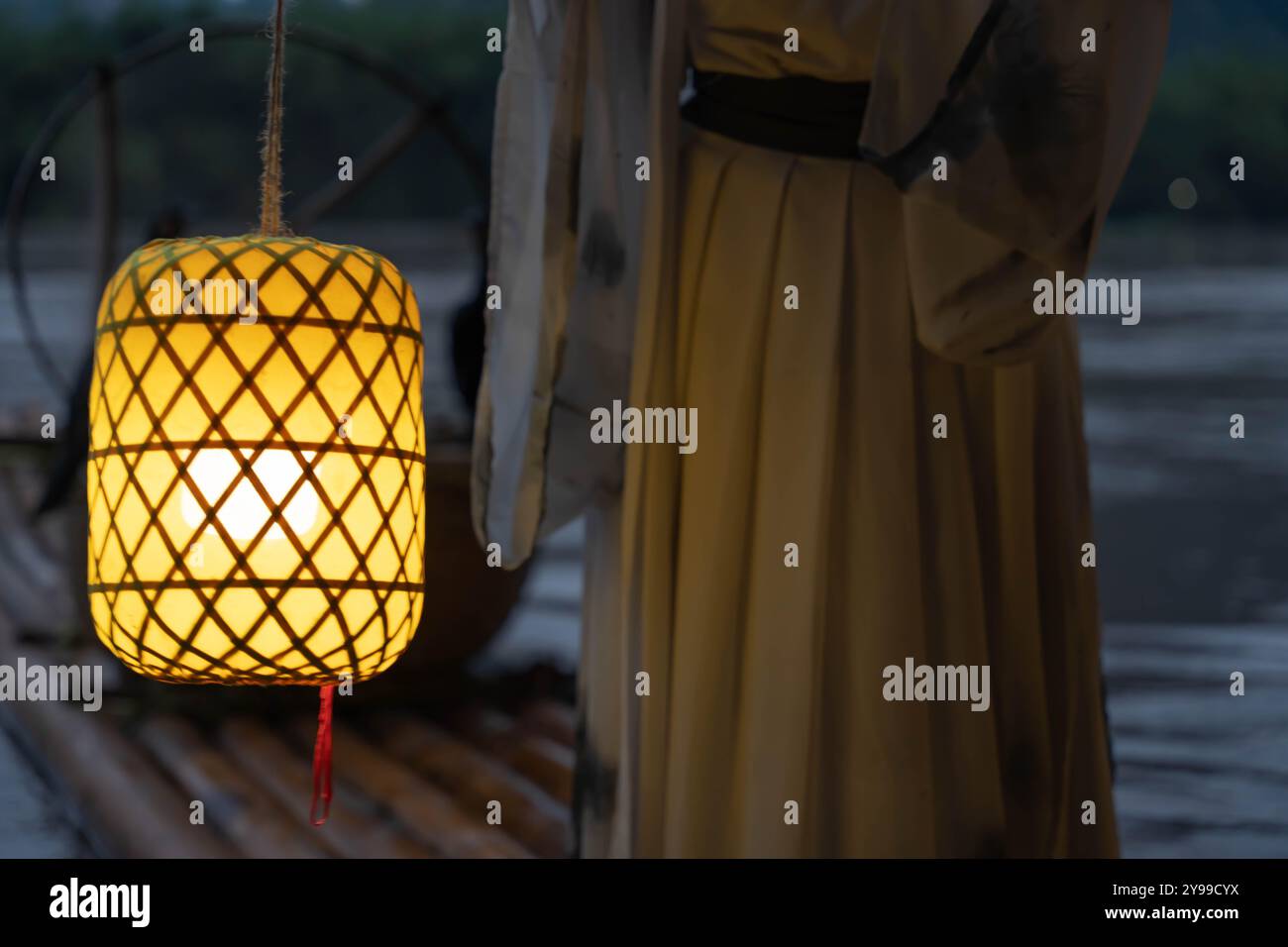 Hanfu Mädchen hält nachts eine beleuchtete Laterne auf einem Bambusfloß Stockfoto