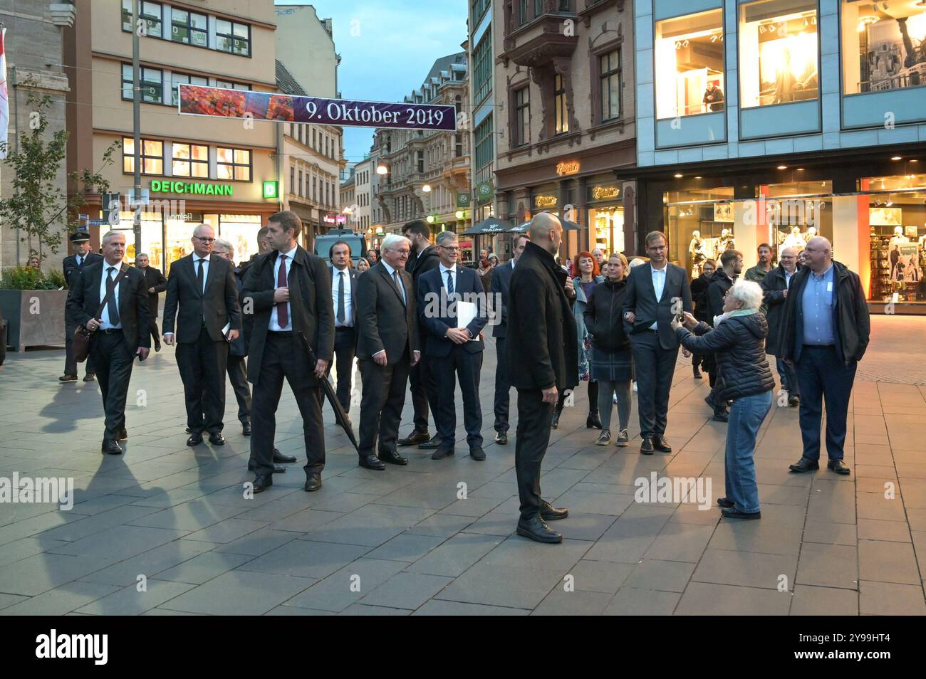 09. Oktober 2024, Sachsen-Anhalt, Halle (Saale): Eine ältere Frau (r) macht ein Foto von Bundespräsident Frank-Walter Steinmeier (ml) und Egbert Geier (Mr), Bürgermeister von Halle, auf dem Marktplatz zu einem Gebetsgottesdienst für die Opfer des Terroranschlags 2019. Am 9. Oktober 2019 versuchte ein schwer bewaffneter Attentäter, die Synagoge am Jom Kippur, dem höchsten jüdischen Feiertag, zu betreten. Als er versagte, erschoss und tötete er zwei Menschen auf der Straße und in einem Kebab-Laden. Foto: Heiko Rebsch/dpa Stockfoto