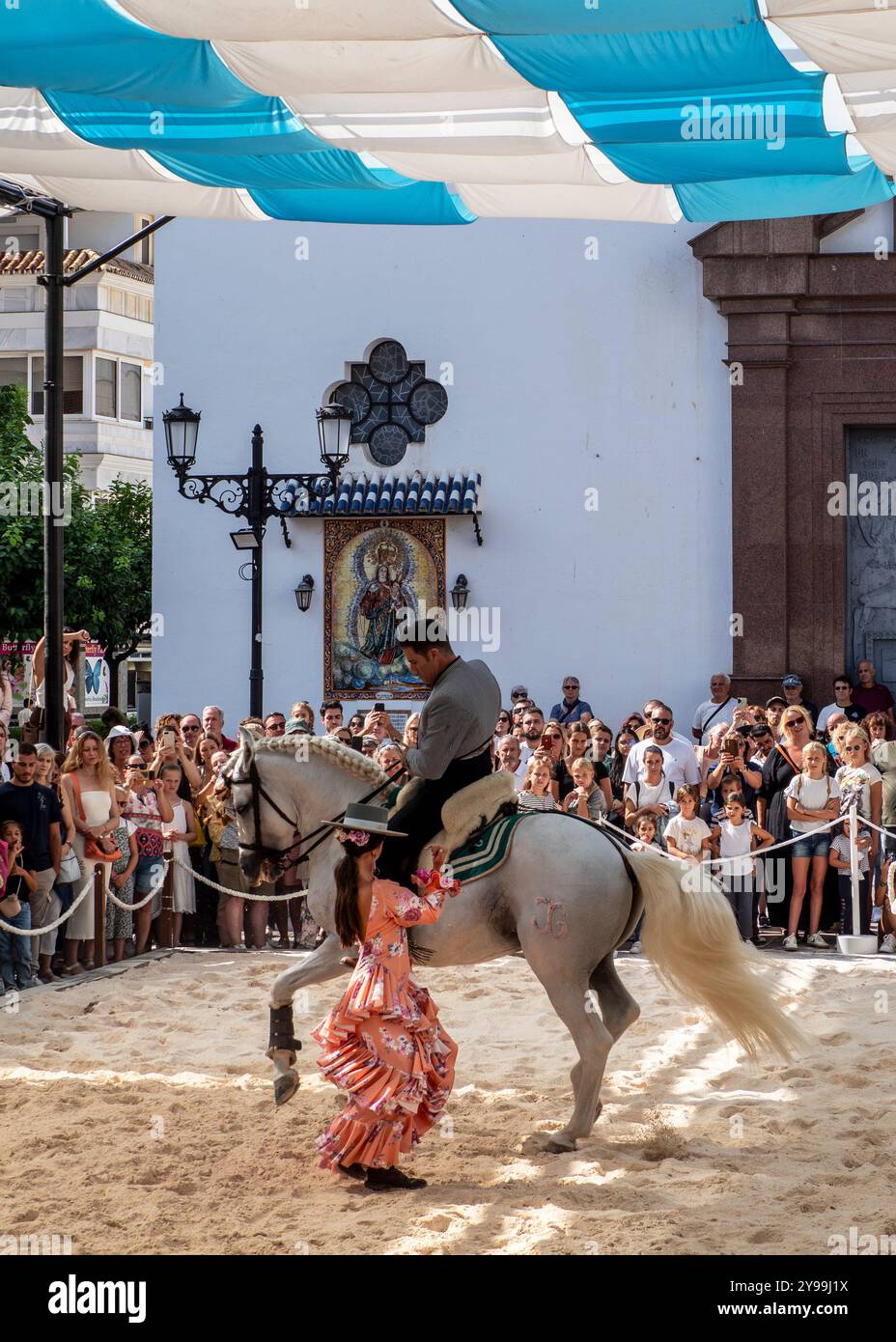 Fuengirola, Malaga, Spanien. Reiter und Tänzer in rosa Flamenco-Kleid und Hut, die während der Messe eine Nachbildung eines Sevillanentanzes vorführen Stockfoto