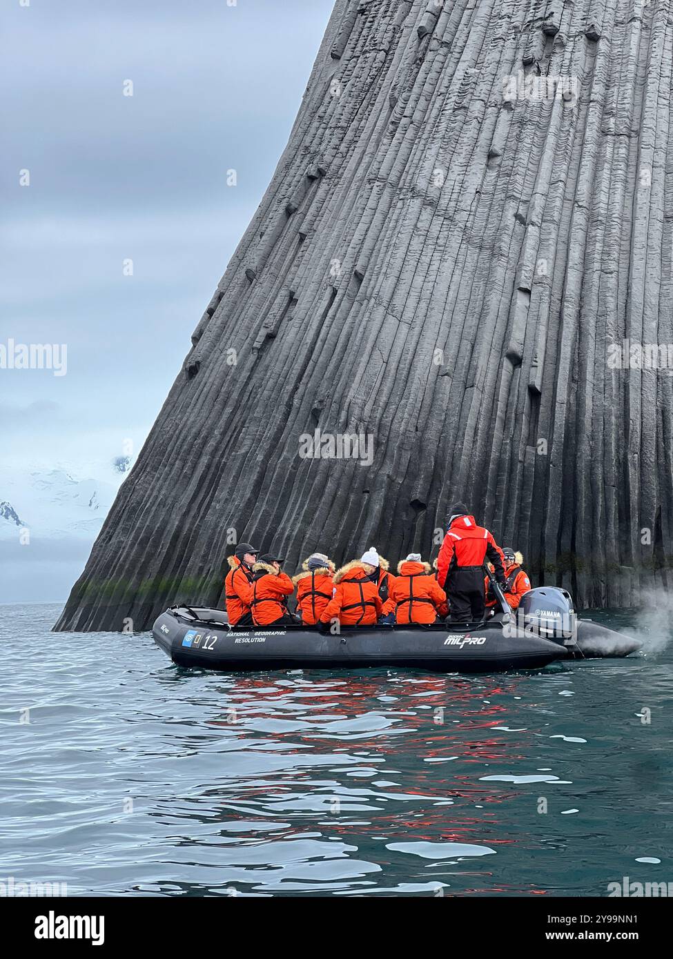 Touristen in orangefarbenen Jacken erkunden die gewaltigen geologischen Formationen des Edinburgh Rock, der sich auf den abgelegenen South Shetland Islands in der Antarktis befindet Stockfoto