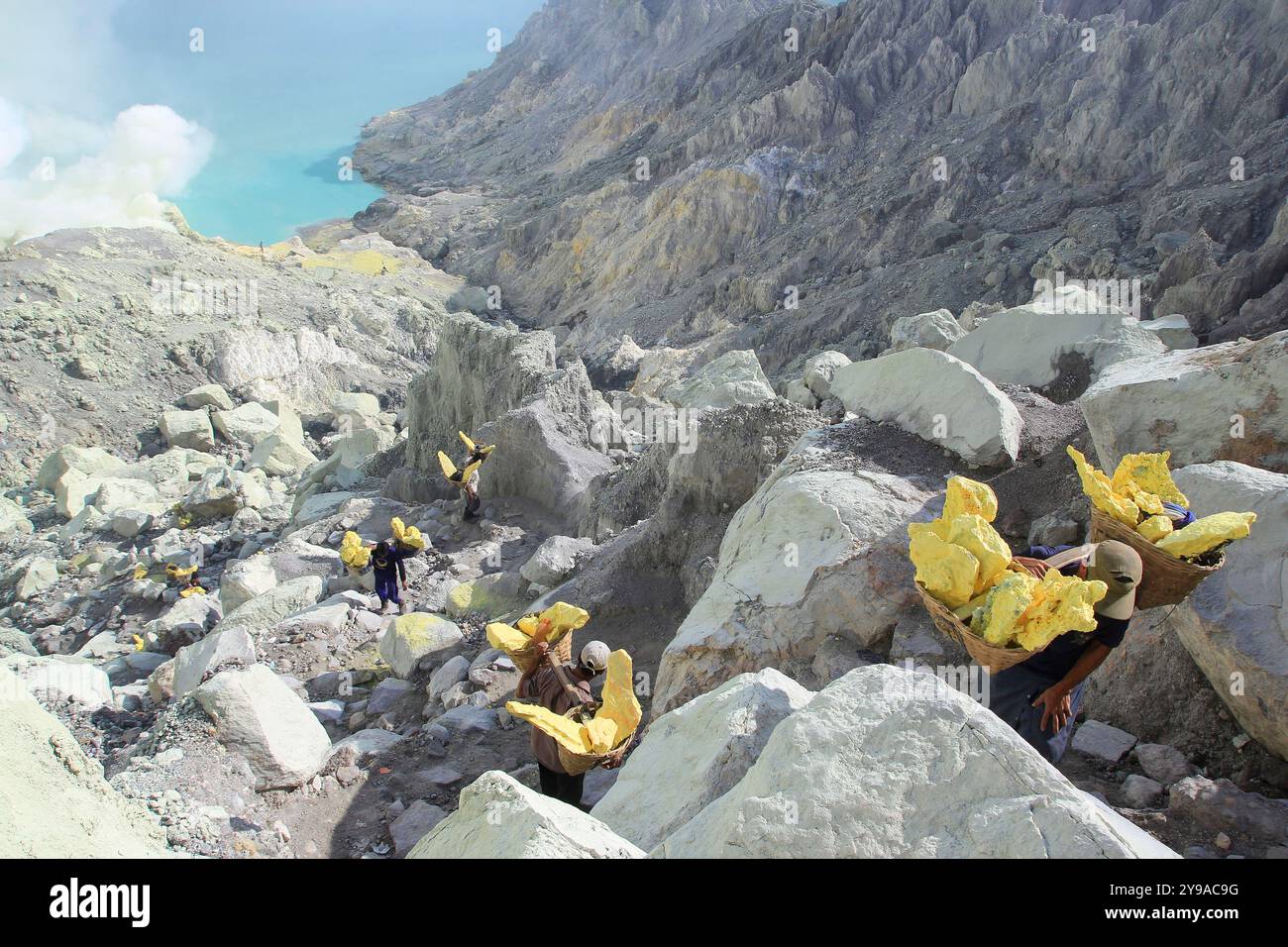 Schwefelbergleute besteigen die Caldera-Wände des Kraters Ijen mit einer durchschnittlichen Belastung von 90 kg. Stockfoto