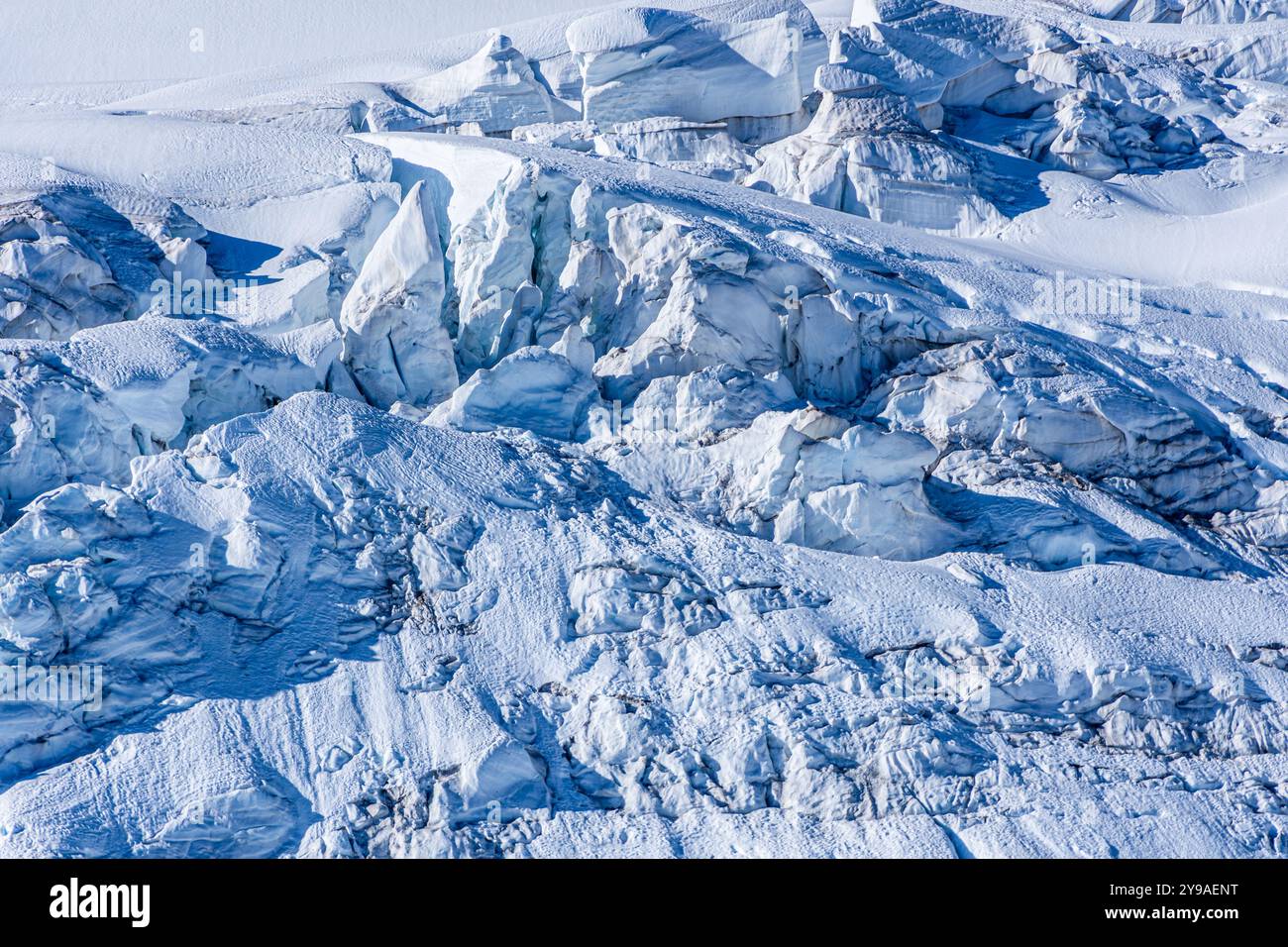 Schnee- und Eisformationen auf der Spitze eines Berggletschers in großer Höhe sehen aus wie eine Mini-Bergkette und schaffen eine interessante Textur. Stockfoto