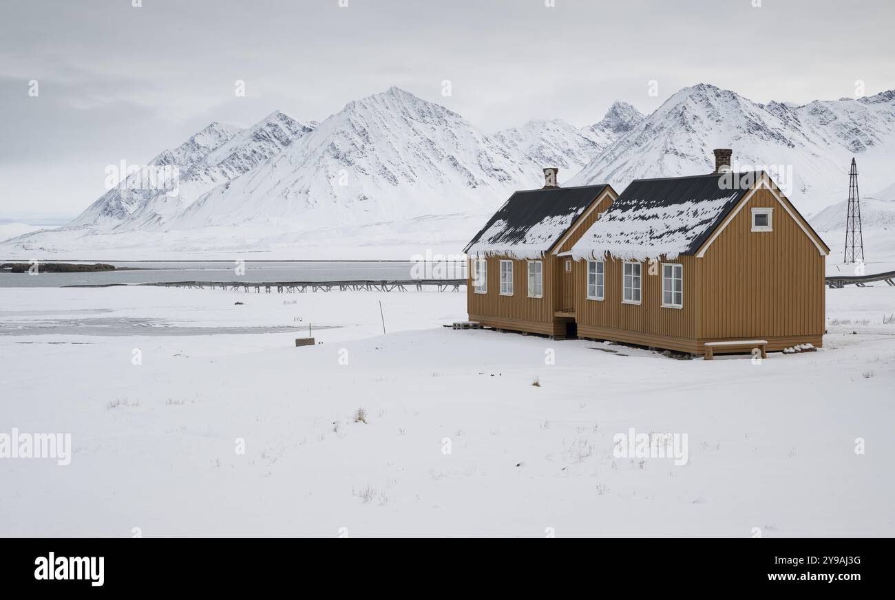 Ockerfarbene Häuser, Forschungssiedlung, wissenschaftliche Siedlung, winterliche Berglandschaft, NY-Alesund, Kongsfjord, Spitzbergen, Svalbard an Stockfoto