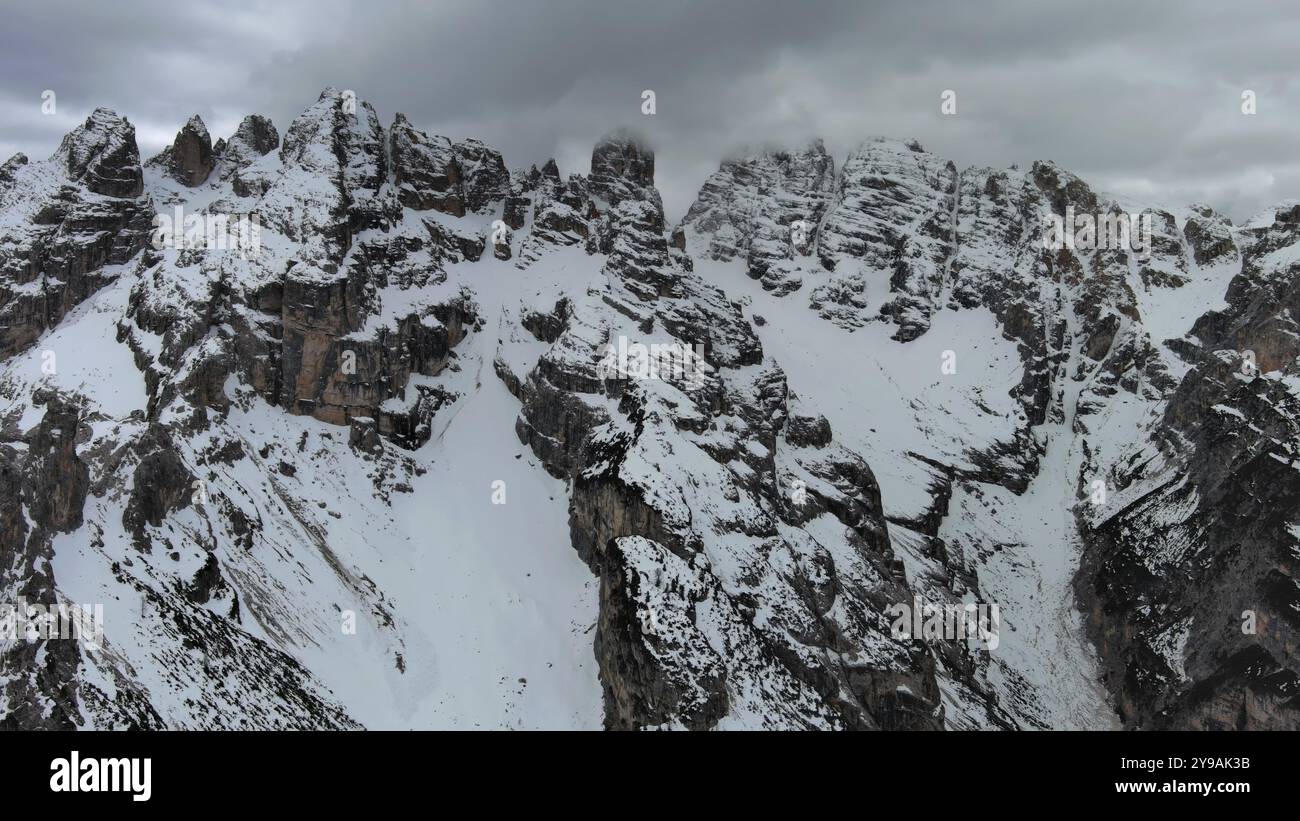 Aus der Vogelperspektive auf atemberaubende felsige Berge im Schnee unter stimmungsvollen grauen Wolken, Dolomiten, Italien, Europa Stockfoto