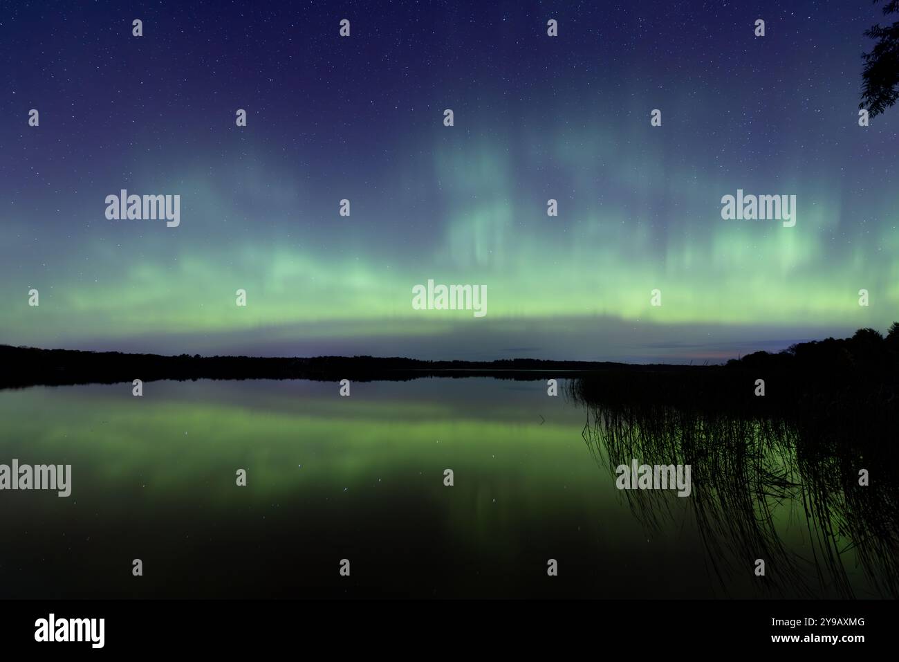 Am 7. Oktober 2024 brechen Nordlichter über einem See in Minnesota aus und erstrahlen einen hellen Regenbogen aus Aurora-Licht und Farben Stockfoto