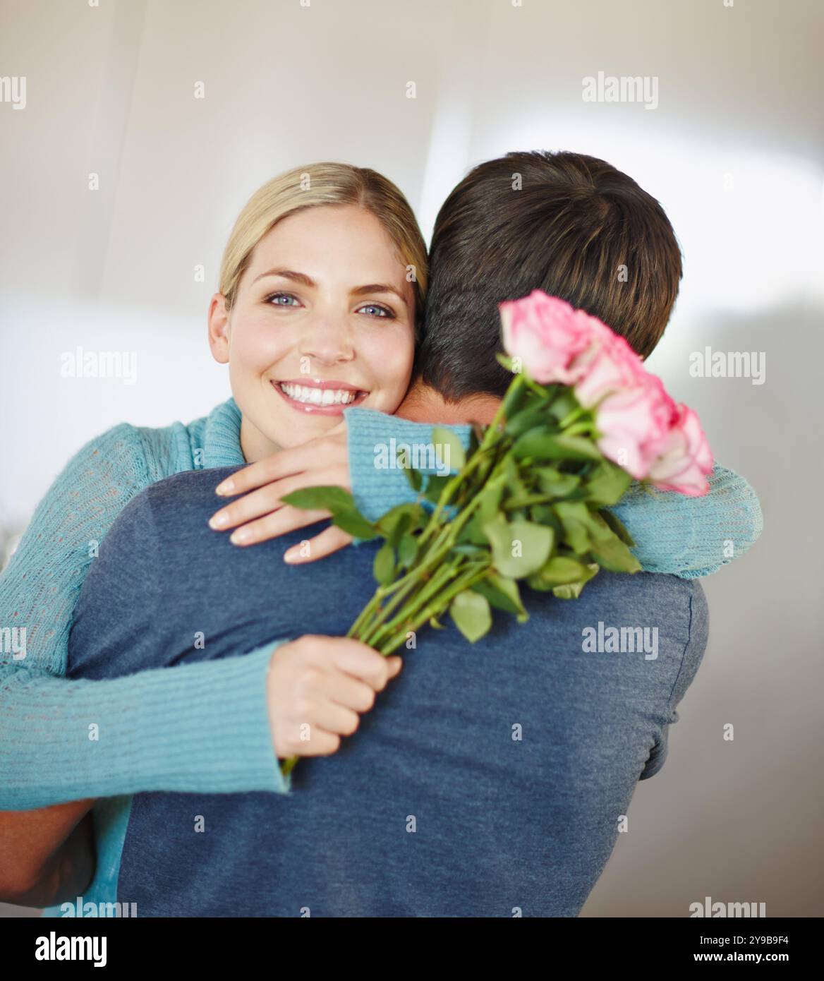 Porträt, Umarmung und Paar mit Blumen, Bindung und Wertschätzung für Partner, glücklich und lächeln zu Hause. Umarmen, Mann und Frau mit Blumenstrauß, Geschenk und Stockfoto