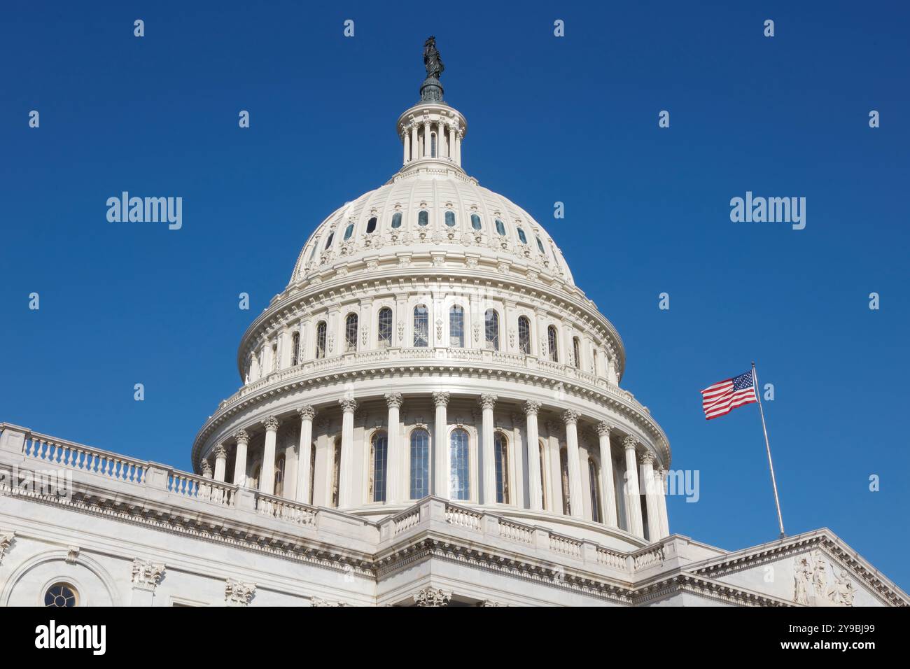 Die berühmte Kuppel des Kapitols der Vereinigten Staaten in Washington, D.C., mit der amerikanischen Flagge, die auf der rechten Seite winkt. Stockfoto