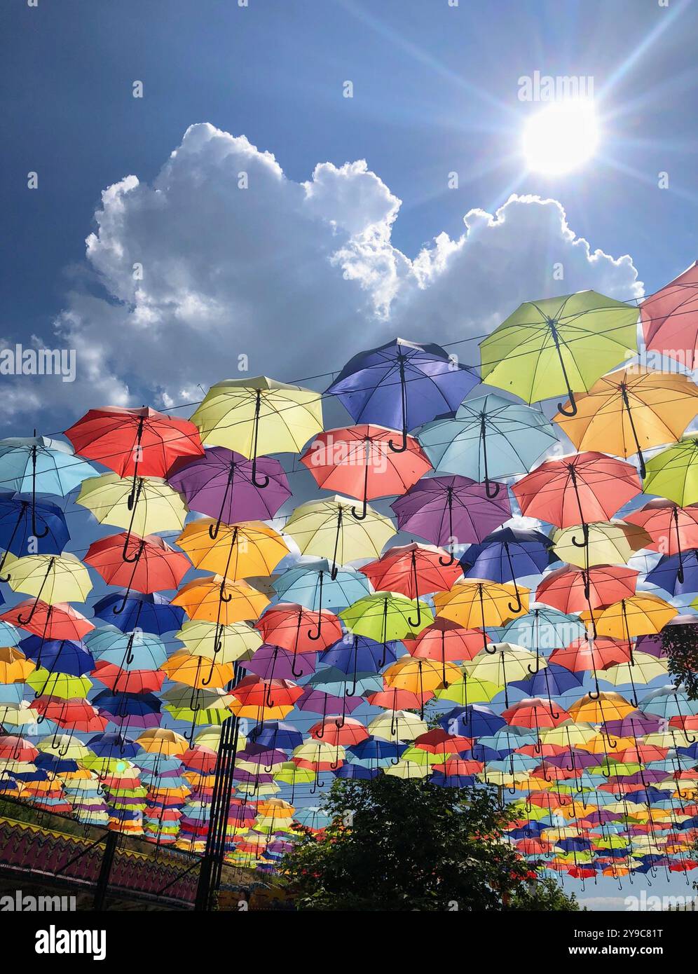 Installation von schönen bunten offenen Regenschirmen in Linien gegen blauen Himmel auf der Arcadia Gasse an einem sonnigen Tag in Odessa, Ukraine - Smartphone-aufgenommenes Stockfoto