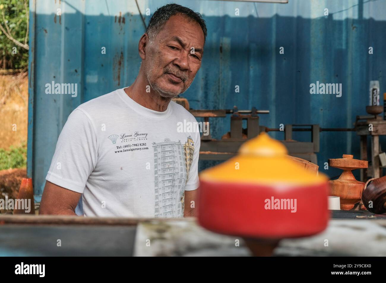 WAK Aziz prüft die Qualitätskontrolle des Drehverschlusses, nachdem der gesamte Prozess in Klang, Selangor, abgeschlossen war. Gasing Pangkah gehört zu den traditionellen malaiischen Sportarten und ist ein Wettkampf, bei dem zwei Gruppen die Spitzenkonkurrenz schlagen, um sich gegenseitig zu gewinnen. Aziz Shamsudin, 63, bekannt als WAK Aziz, ist ein traditioneller Spinning Top Maker in Selangor. Seit seinen 30ern bis heute fertigt WAK Aziz das traditionelle Spinning-Top, und heute gibt WAK Aziz die Handwerkskunst an Mohd Zaimi, auch bekannt als Jimmie, 49, weiter, der zu den Schützlingen der WAK Aziz gehört, um das Erbe fortzuführen. Nicht Stockfoto