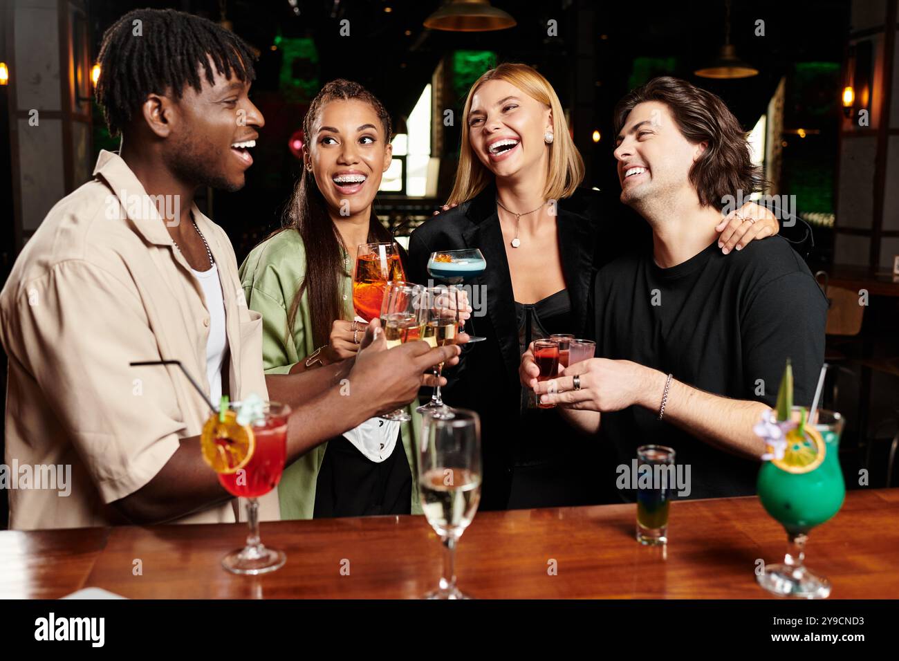 Kollegen feiern mit Lachen und bunten Cocktails bei einer Abendveranstaltung. Stockfoto