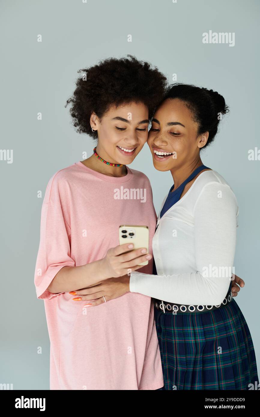 Zwei Freunde lächeln, während sie gemeinsam ein Telefon betrachten. Stockfoto